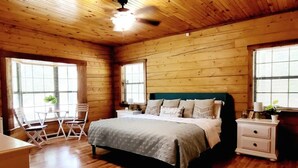 A wooden-paneled bedroom with a bed, bedside tables, and a window. - Spacious log cabin for country getaway (Teague)