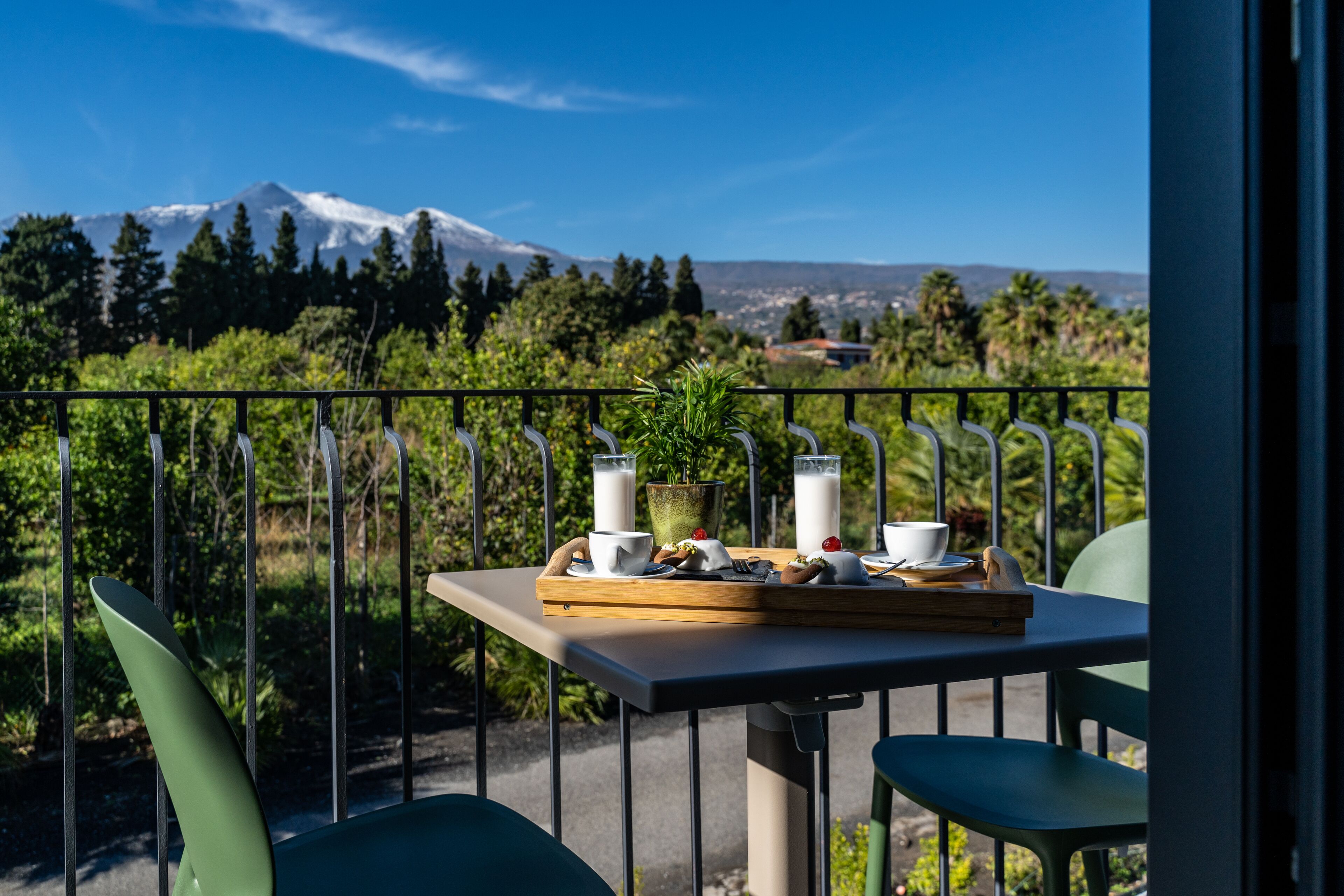 Ein Balkon mit Frühstückstisch, mit Blick auf Berge und Grünflächen.