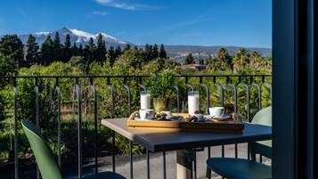 Ein Balkon mit Frühstückstisch, mit Blick auf Berge und Grünflächen.