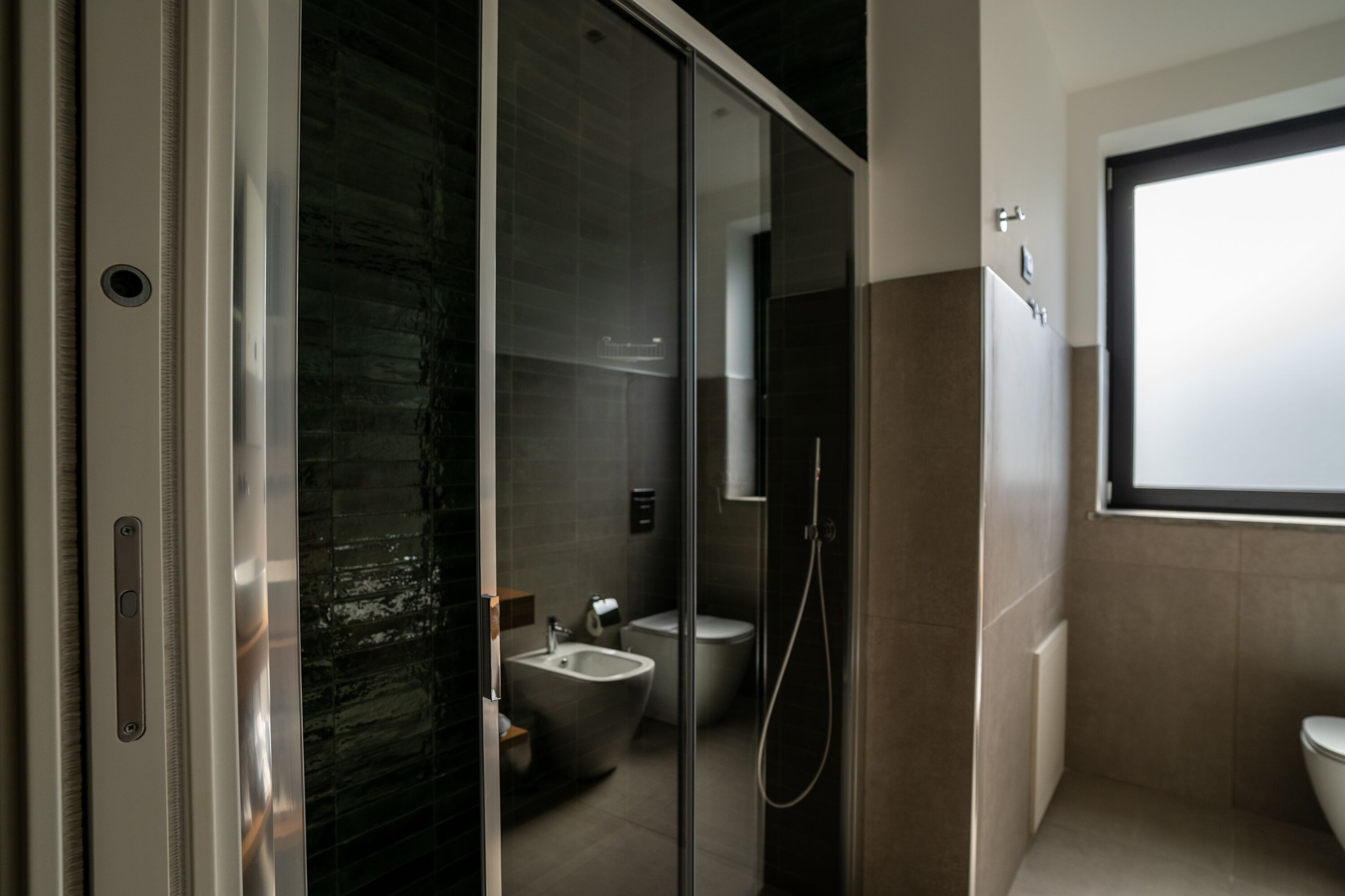 A modern bathroom with a glass shower enclosure, a bidet, and a toilet.
