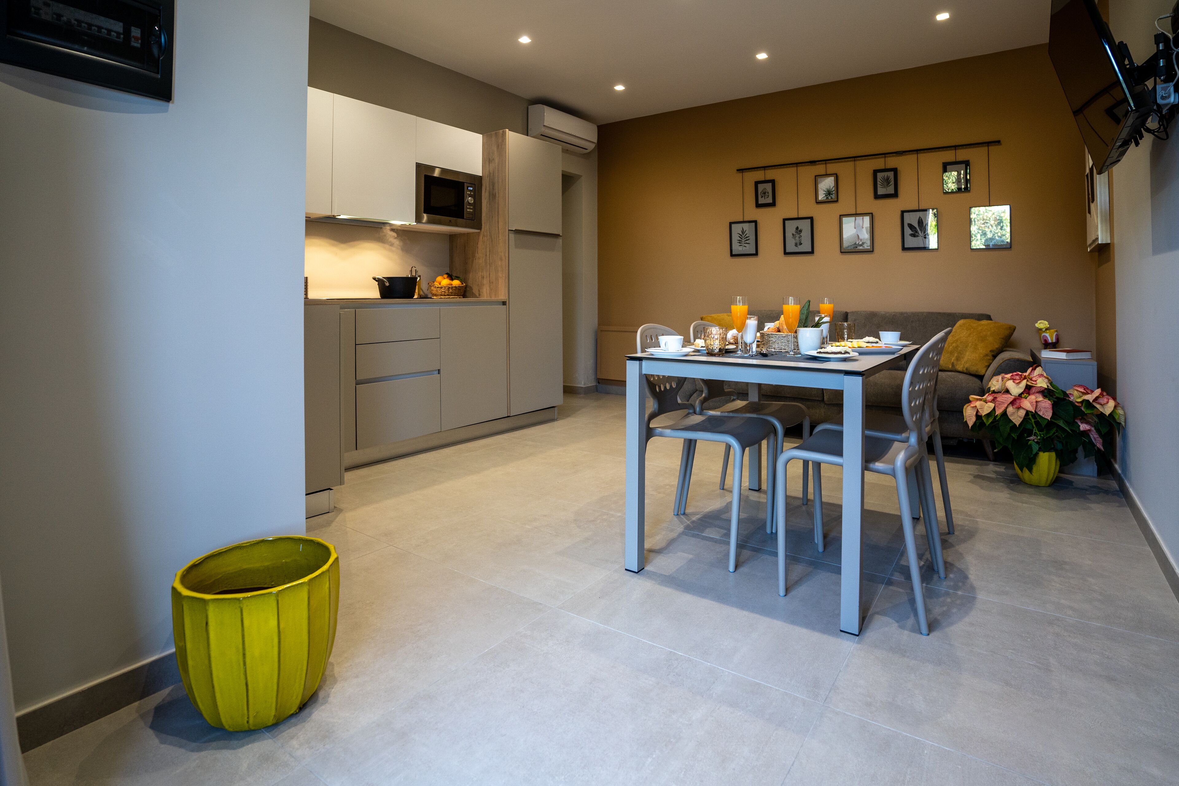 Cocina moderna con comedor, que incluye una mesa con sillas, un sofá y una planta pequeña.