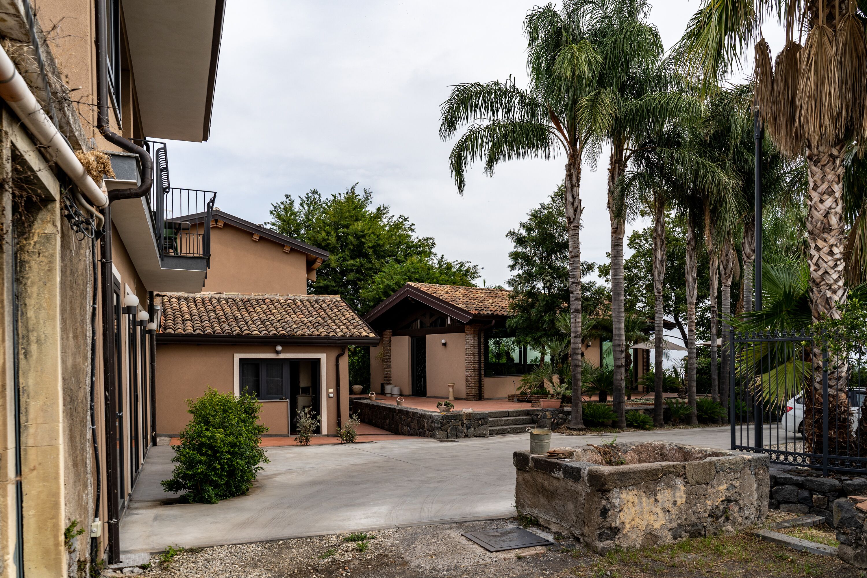 A residential area with a house featuring a tiled roof, a balcony, and a stone pathway leading to the entrance.
