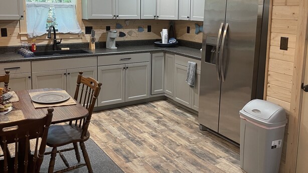 Eine moderne Küche mit Holzausstattung, einem Edelstahlkühlschrank und einem Essbereich mit Tisch und Stühlen.