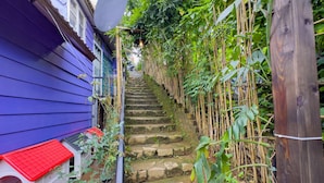 A narrow stone staircase leading up to a house with a satellite dish and a small white structure with a red roof. - Gio Homestay  (Xuan Huong - Da Lat)