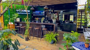 An outdoor bar area with a wooden counter, bar stools, and various plants. - Gio Homestay  (Xuan Huong - Da Lat)