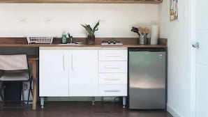Een kleine keuken met witte kastjes, een roestvrijstalen koelkast en een houten aanrecht.