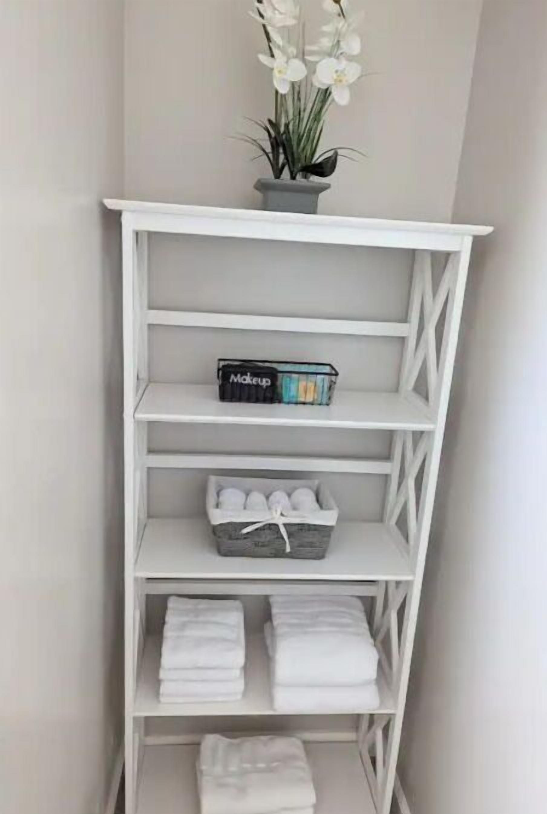 Een witte plank met een potplant, make-up en opgevouwen handdoeken.