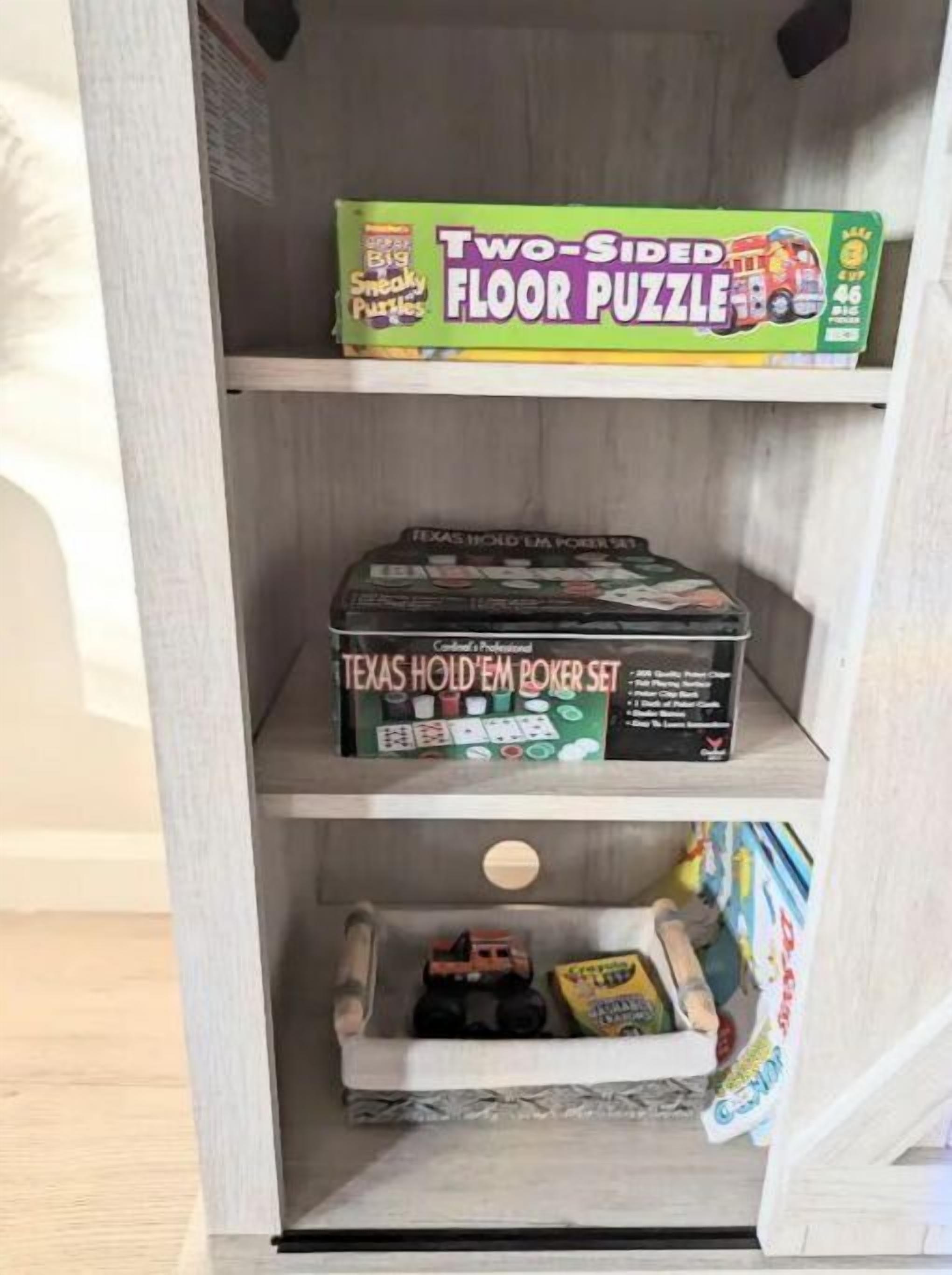 A shelf with a two-sided floor puzzle, a Texas Hold'em poker set, and a toy car.