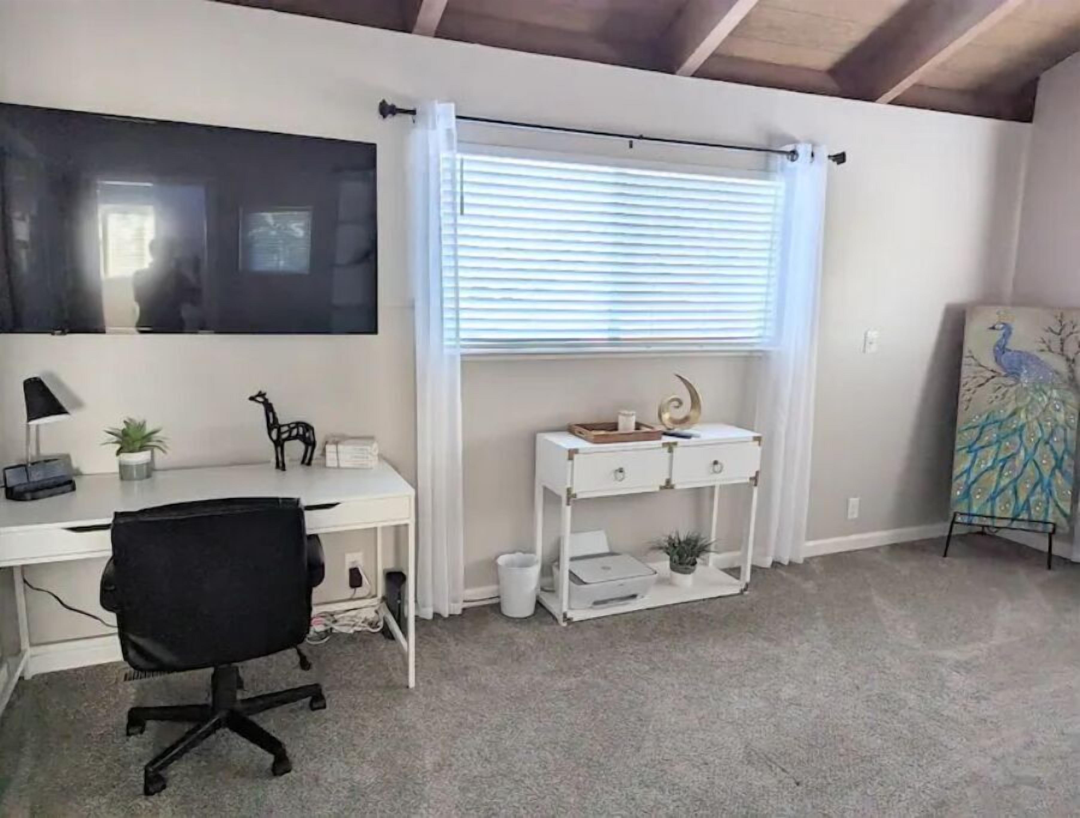 A modern office space with a desk, chair, and a large window with blinds.