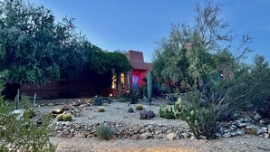 A desert garden with cacti and a building with red and blue lighting. - Charming Adobe Casita! Large lot in upscale quiet neighborhood. STR 15734641 (Fountain Hills)