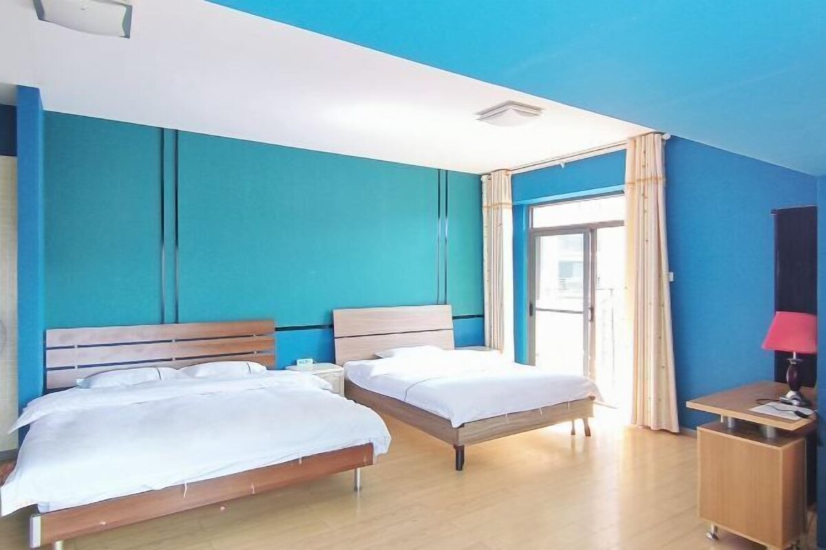 A hotel room with two beds, a desk, and a window with curtains.