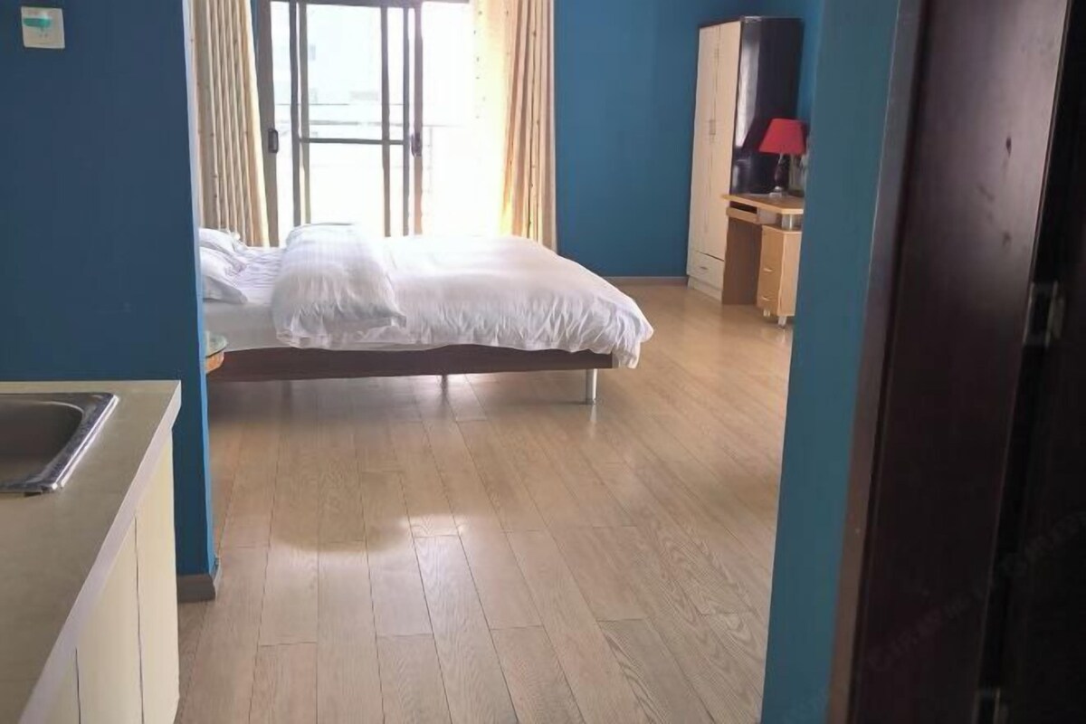 A bedroom with a bed, a desk, and a wardrobe.