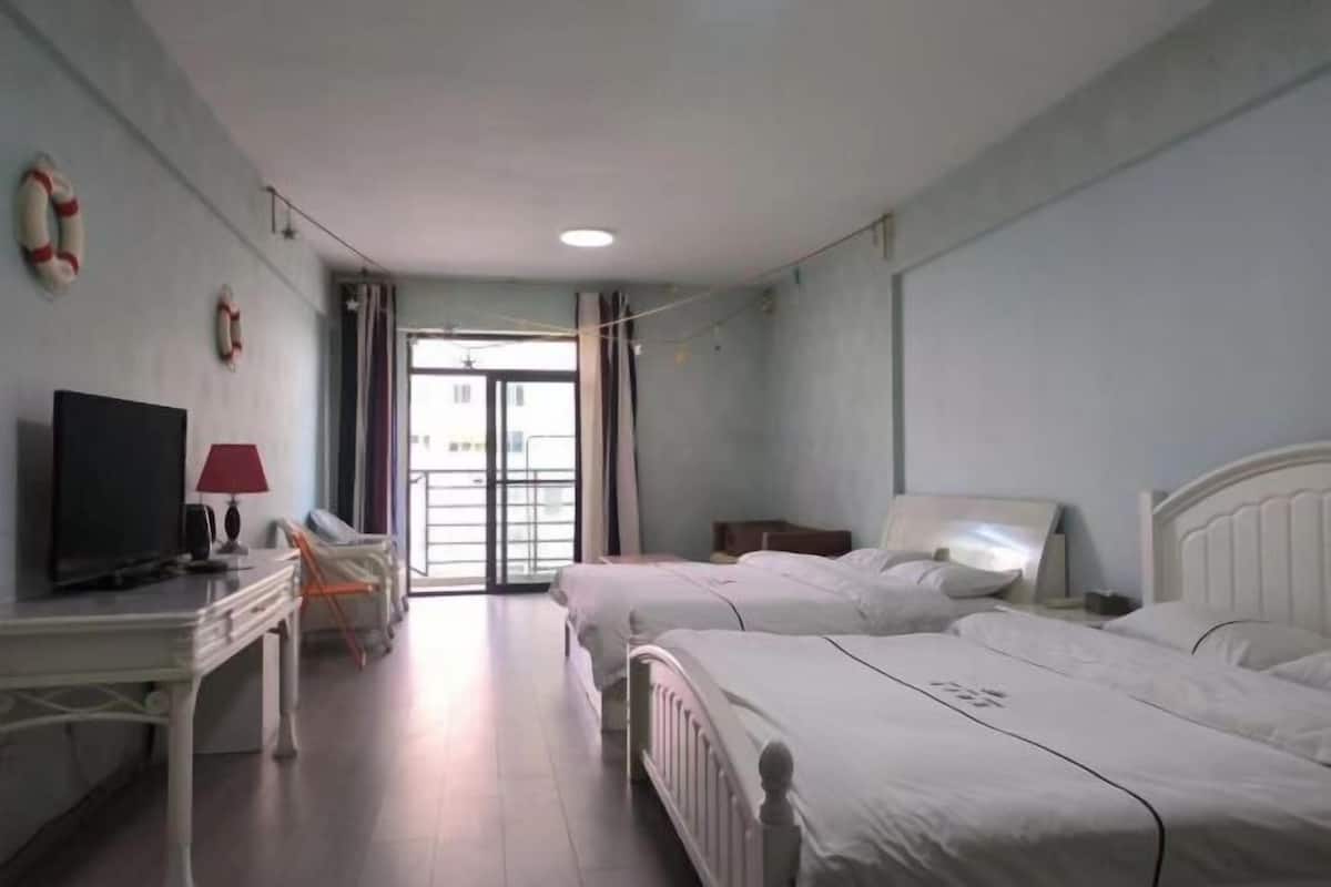 Ein Hotelzimmer mit zwei Betten, einem Schreibtisch mit Fernseher und einem Fenster mit Vorhängen.