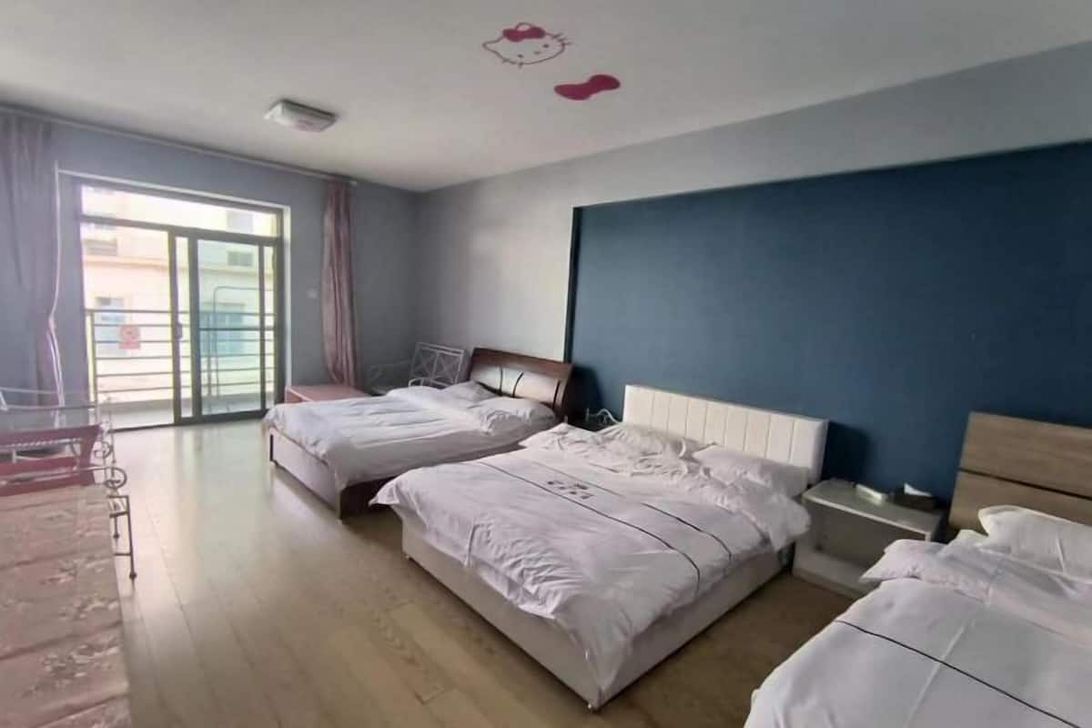 Ein Hotelzimmer mit zwei Betten, einem kleinen Nachttisch, einem Sessel und einem großen Fenster mit Vorhängen.