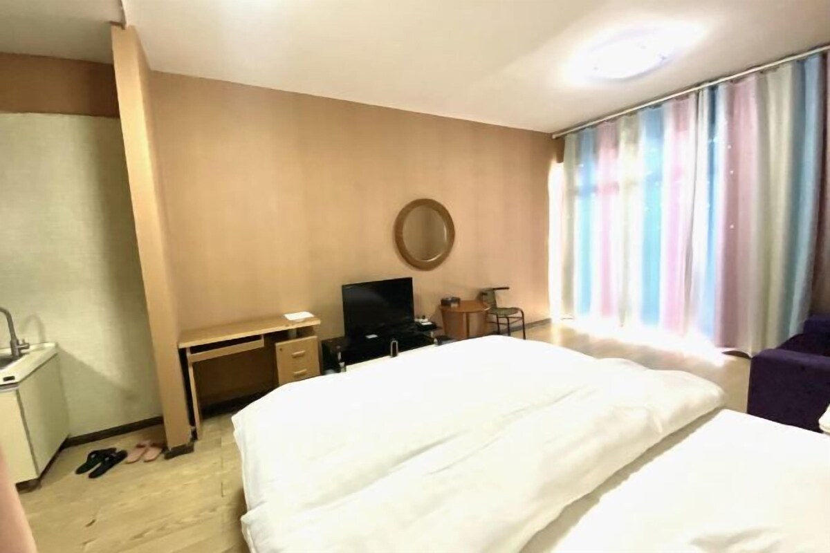 A hotel room with a bed, a desk, a television, and a chair.