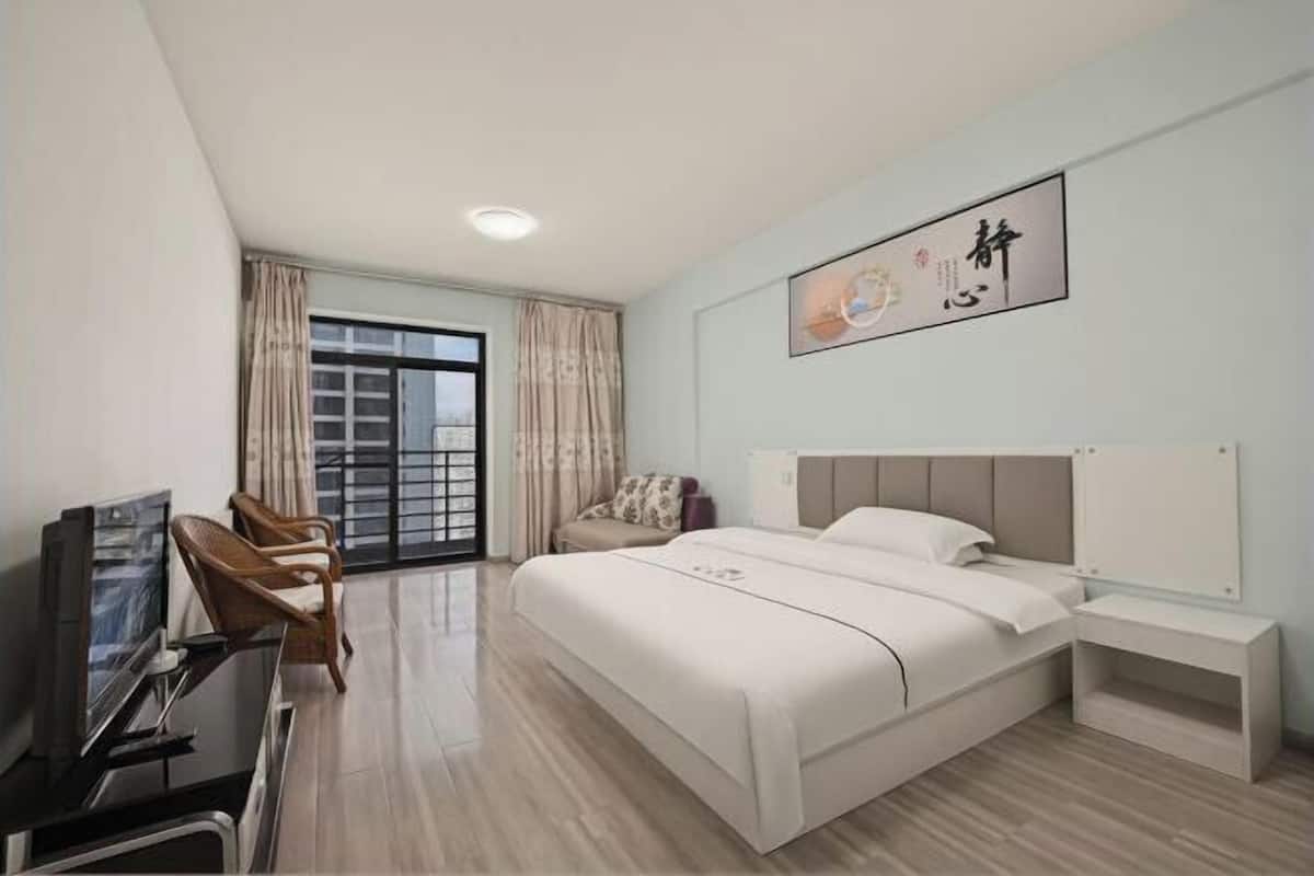 Ein modernes Hotelzimmer mit einem großen Bett, einem Fernseher, einem Schreibtisch und einem Fenster mit Vorhängen.
