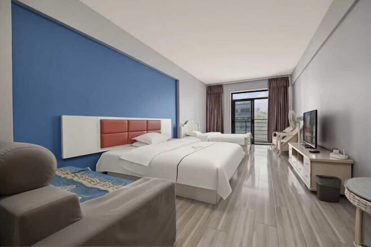 Ein Hotelzimmer mit zwei Betten, einem Fernseher, einem Schreibtisch und Blick auf die Stadt.
