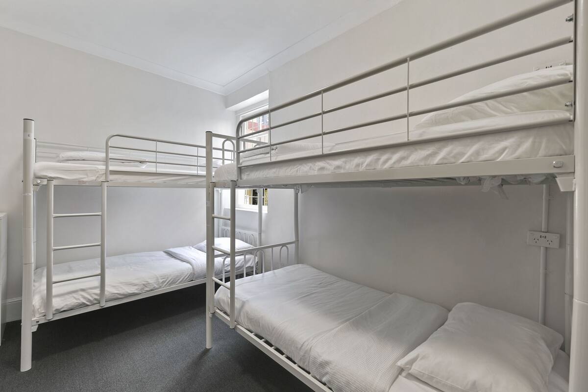 A bunk bed room with two beds, a window, and a power outlet.