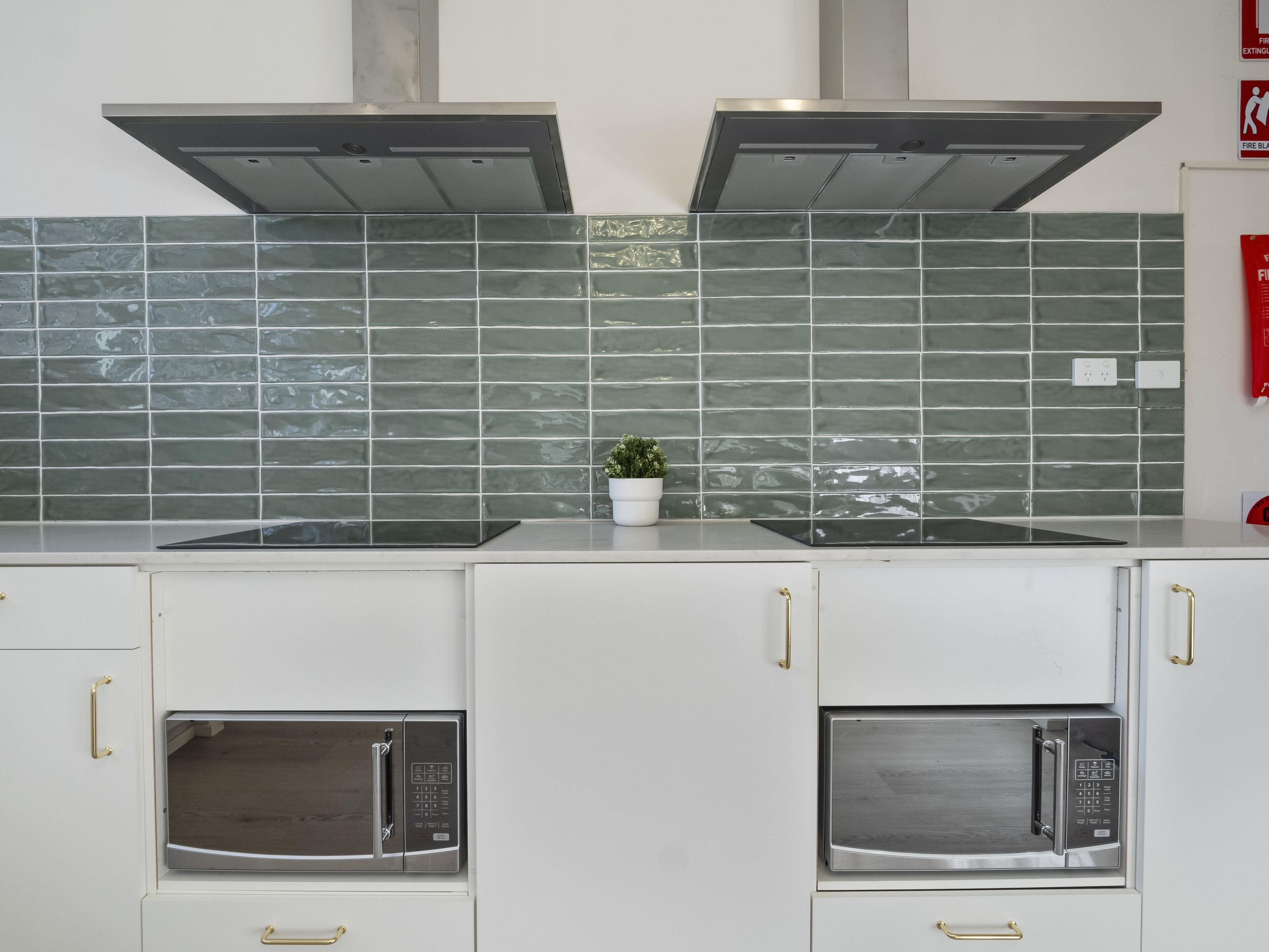 A kitchen with two built-in microwaves, a stove, and a tiled backsplash.