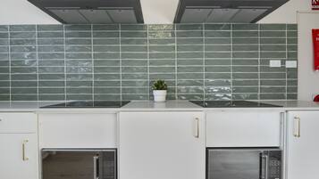 A kitchen with two built-in microwaves, a stove, and a tiled backsplash.