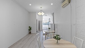 A modern kitchen with white cabinets, a wooden countertop, and a hanging light fixture. - Urban Nomad Potts Point - 18-39 (Potts Point)