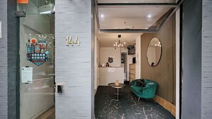 An interior view of a hostel with a reception desk, a green sofa, and a mirror on the wall. - Urban Nomad Potts Point - 18-39 (Potts Point)