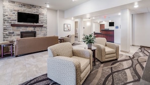 A lobby with a stone fireplace, a flat-screen TV, a reception desk, and comfortable seating. - Cobblestone Inn & Suites - Winters (Winters)