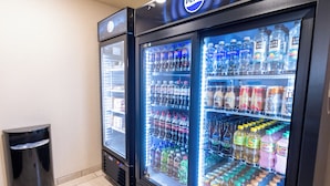 Two refrigerated beverage dispensers stocked with various drinks, including sodas and bottled water, in a commercial setting. - Cobblestone Inn & Suites - Winters (Winters)