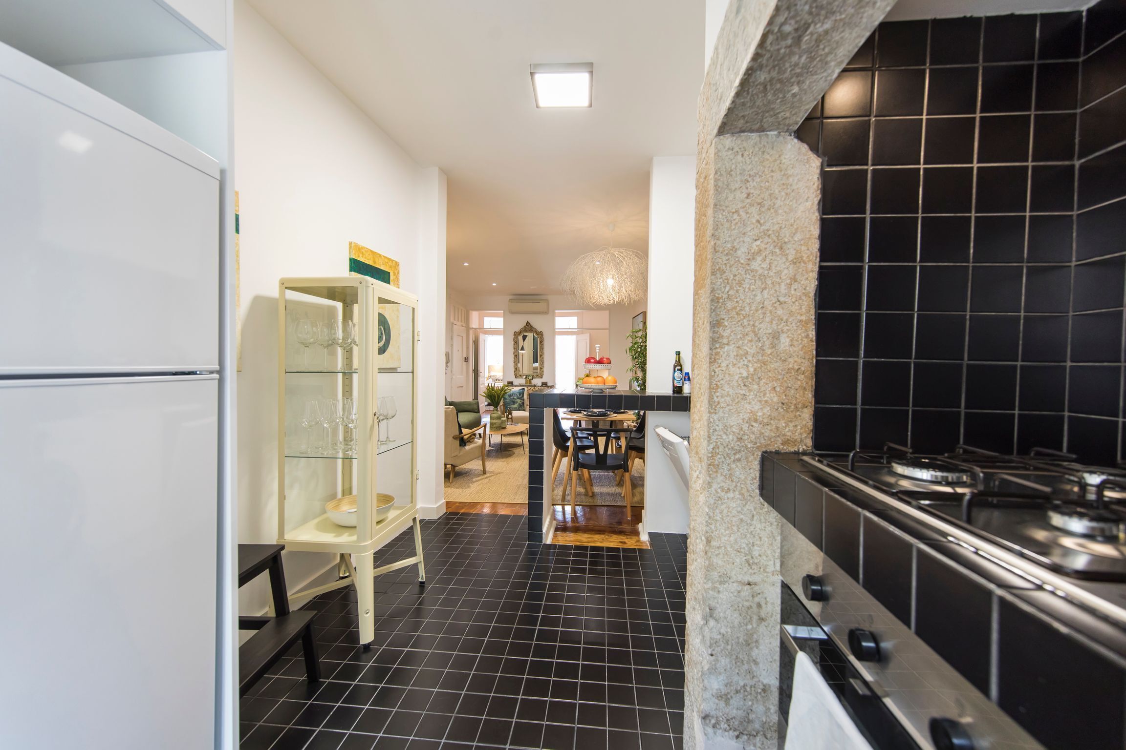 A kitchen with black tiled flooring, a gas stove, and a white refrigerator.
