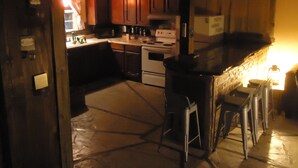 A kitchen with wooden cabinets, a stove, and a bar area with stools. - Nestled in Hill Country- Minutes from multiple attractions (Spring Branch)