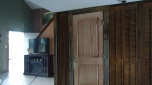 A room with a wooden door, a television on a stand, and a staircase leading to another level. - Nestled in Hill Country- Minutes from multiple attractions (Spring Branch)