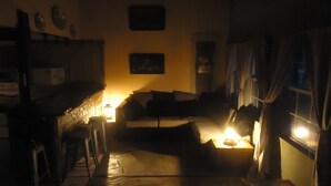 A dimly lit room with a sofa, a small table, and a window with curtains. - Nestled in Hill Country- Minutes from multiple attractions (Spring Branch)