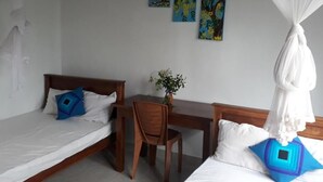 Ett sovrum med två enkelsängar, ett skrivbord i trä och en stol. Det finns tre tavlor på väggen.