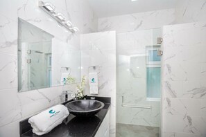Ein modernes Badezimmer mit einem großen Spiegel, einem schwarzen Waschbecken und einer Duschkabine aus Glas.