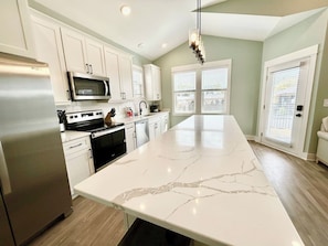 A kitchen with white cabinets, stainless steel appliances, and a large marble countertop.