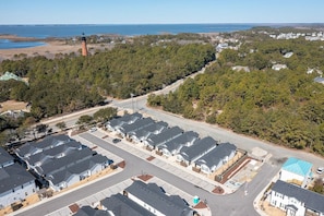 A residential area with multiple houses, a road, and a lighthouse in the background. - Barefoot Bliss - Single Level Steps to the Beach (Corolla)
