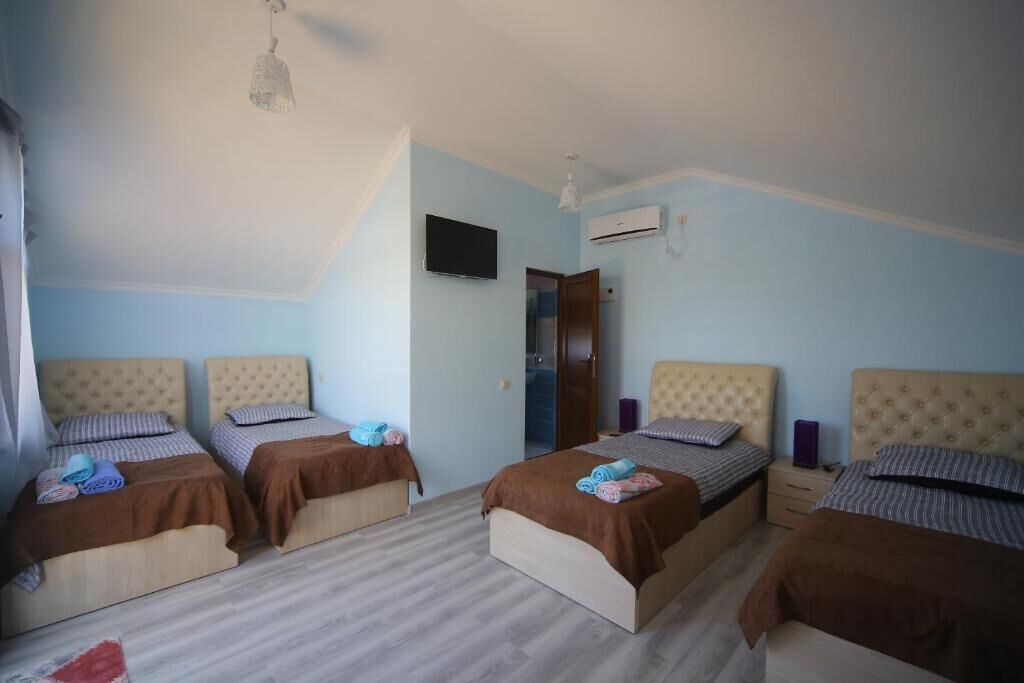 Una habitación con cuatro camas, televisión de pantalla plana, aire acondicionado y ventilador de techo.