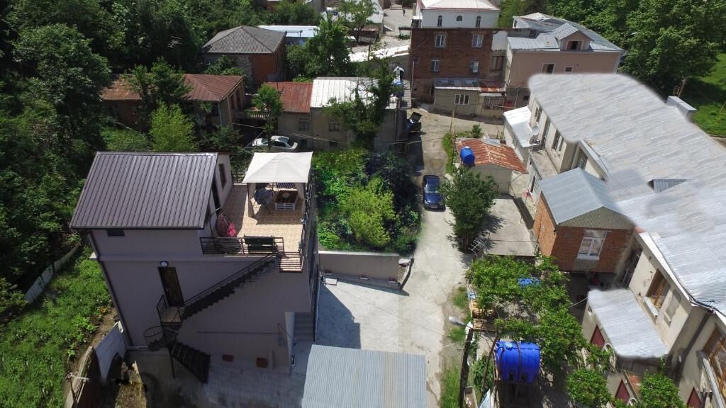 A residential area with multiple houses, a narrow street, and some greenery.