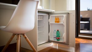 Un petit réfrigérateur compact avec une seule étagère contenant deux bouteilles d’eau et une bouteille de soda.