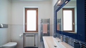 Une salle de bain moderne équipée d’un WC, d’un lavabo, d’un porte-serviettes et d’un miroir.