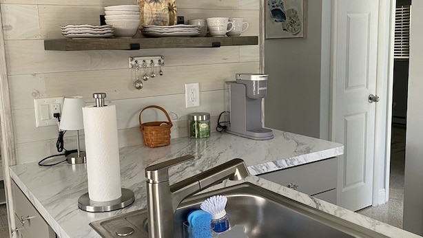 A modern kitchen with a marble countertop, stainless steel sink, and a built-in coffee maker.