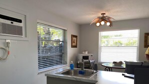 A kitchen with a built-in microwave, a sink, and a window with blinds.