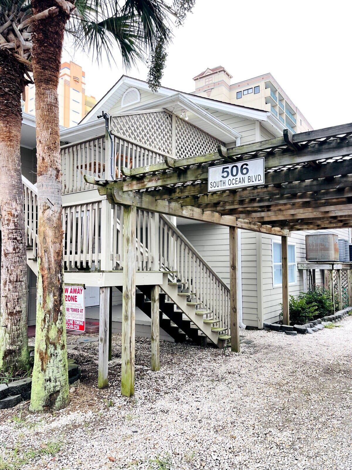 A wooden deck with a sign reading "506 South Ocean Blvd." and a "No Parking" sign.