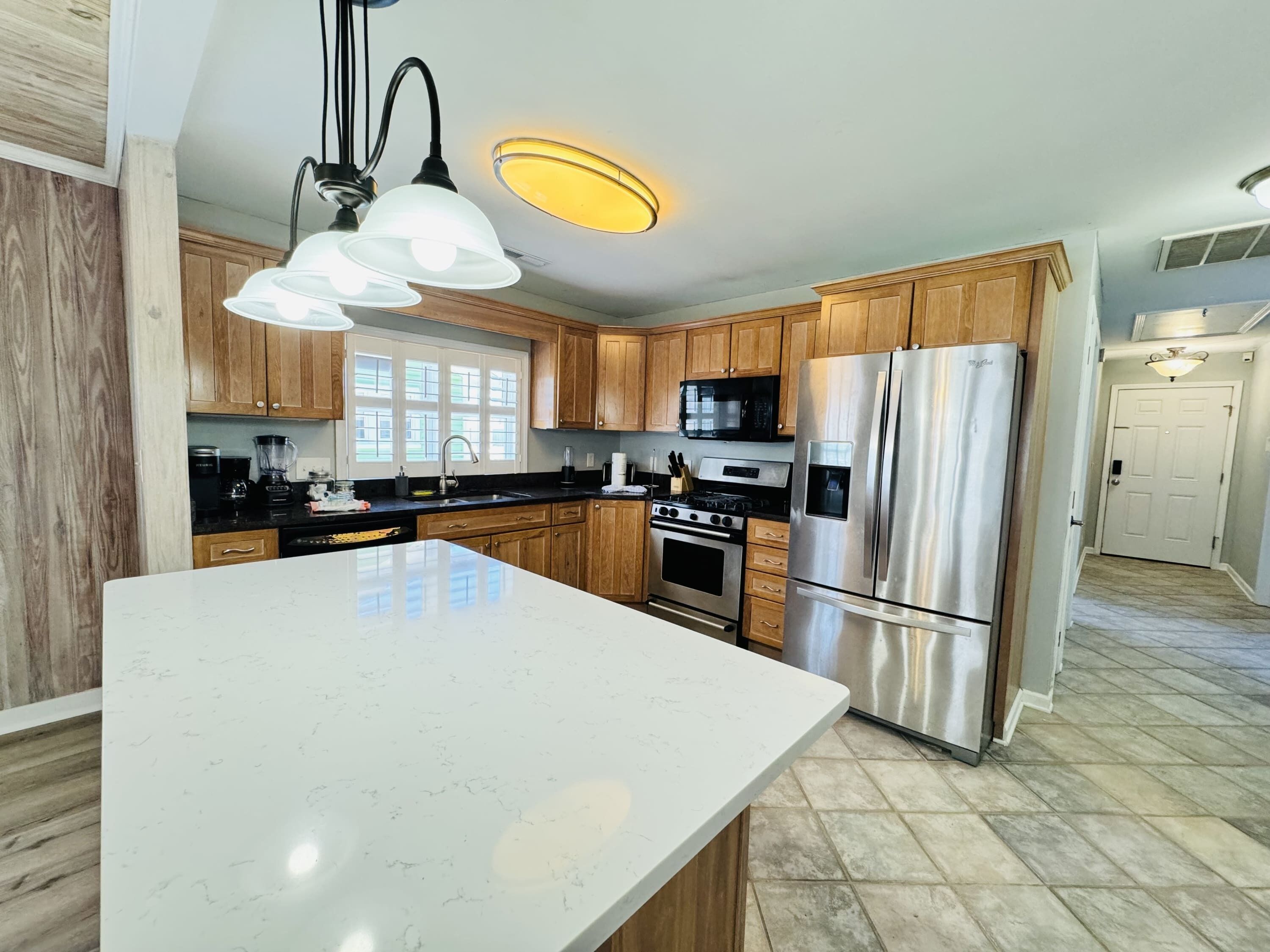 A modern kitchen with wooden cabinets, stainless steel appliances, and a large marble countertop.