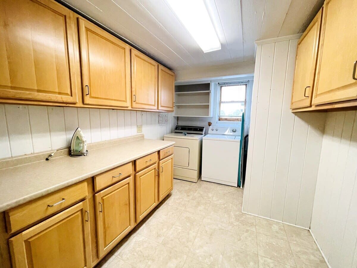 A kitchen with wooden cabinets, a countertop, a stove, and a washing machine.