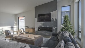 Un salón moderno con un sofá grande de color gris, una mesa de centro de madera y una chimenea.