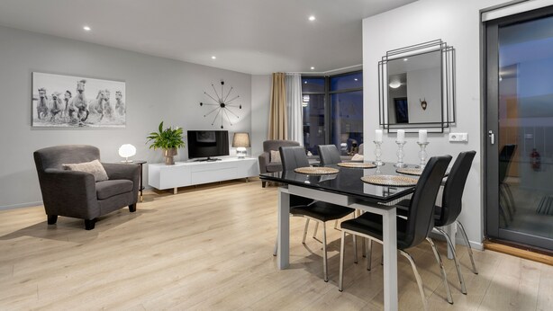 A modern living room with a dining area, featuring a sofa, TV, and a dining table with chairs.