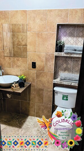 Un baño con lavamanos, inodoro y repisas con toallas.