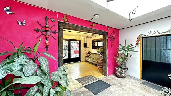 Una entrada vibrante con una pared rosa, un candelabro y una planta en maceta.