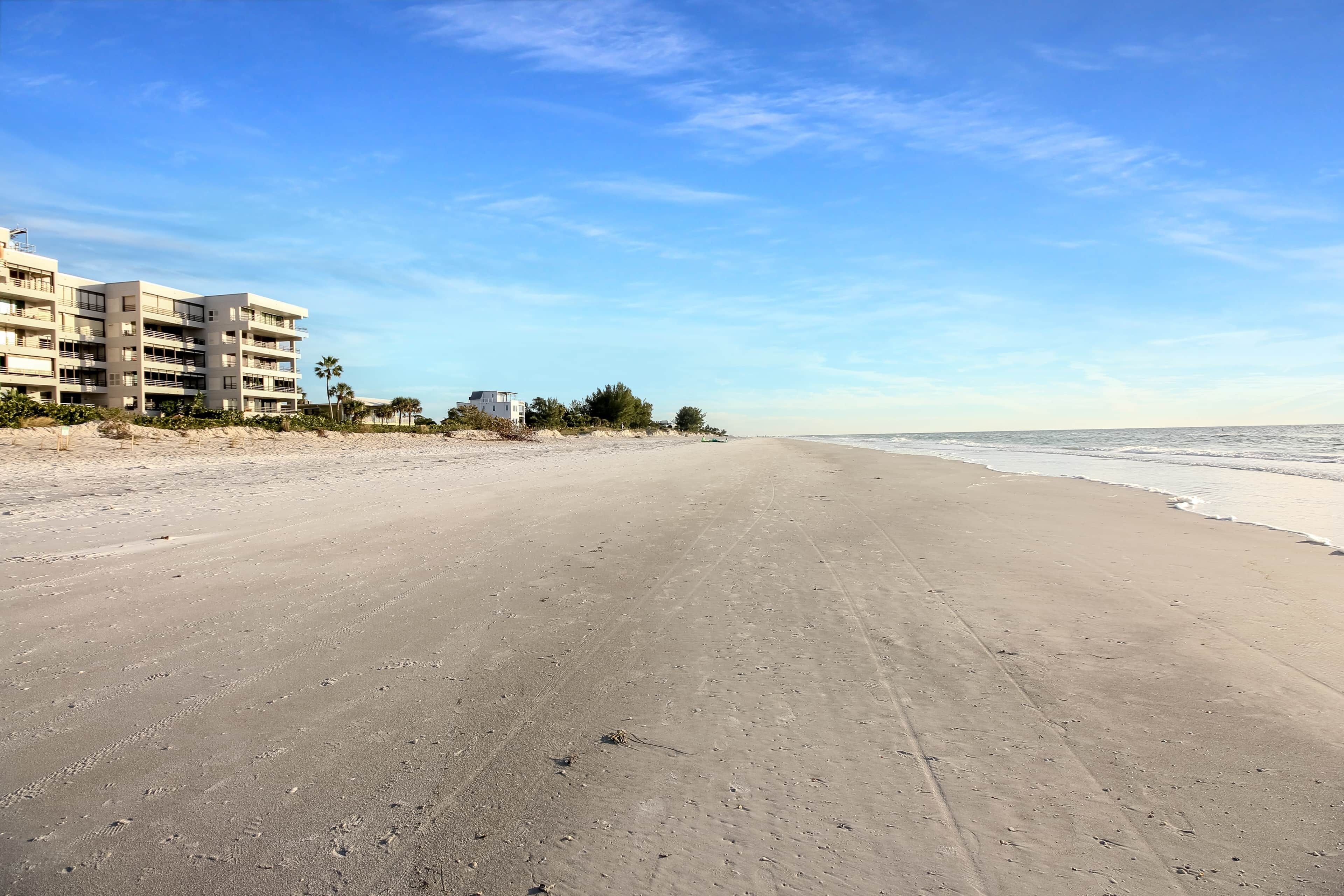 Een strand met een gebouw aan de linkerkant.